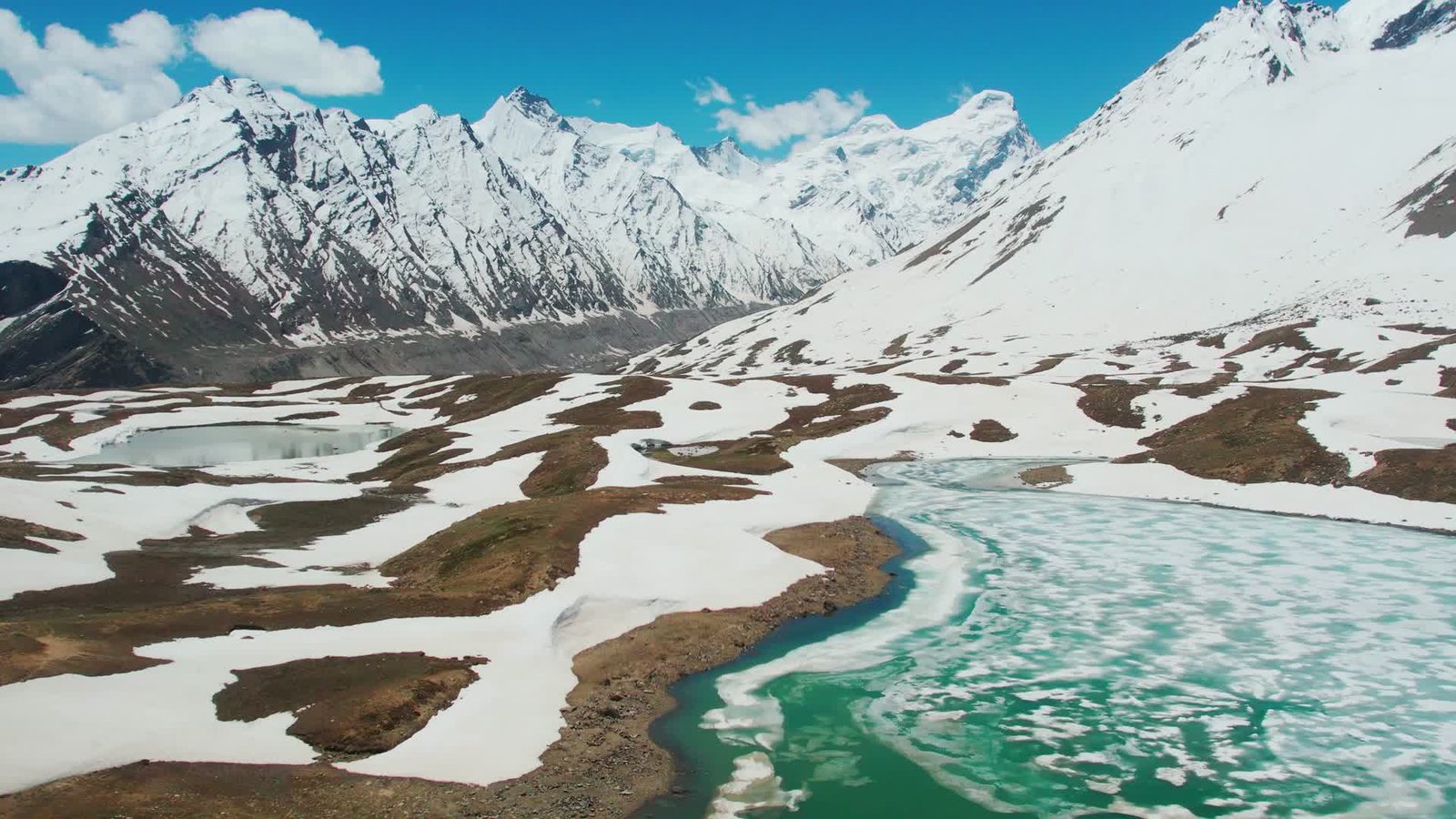 Turquoise mountain lake surrounded by snow-covered peaks in Pakistan