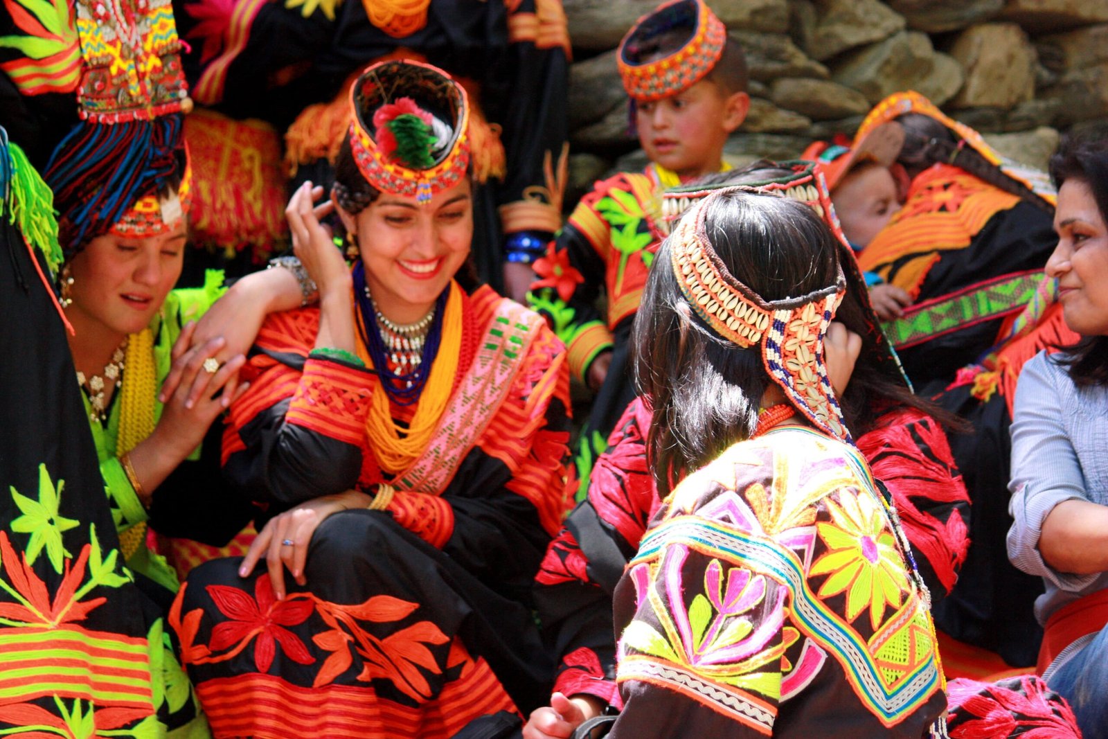 Kalash women and children gathered in colourful traditional embroidered clothing and headdresses in Pakistan